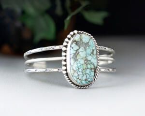 large oval turquoise with brown matrix natural stone bezel set accented with twisted wire and beads on a 3 wire stamped sterling silver cuff